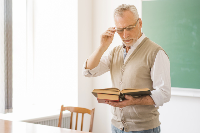 focused male professor glasses reading book classroom